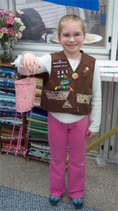 a little girl who is a brownie showing her fabric windsock she made to get her sewing badge