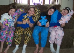 4 girls in pajama pants and holding a pillow and a teddy bear