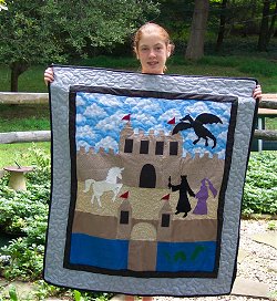 a teen holding a quilt they made of a castle, princess, and unicorn