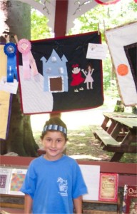 little girl standing next to a quilt she made with an award