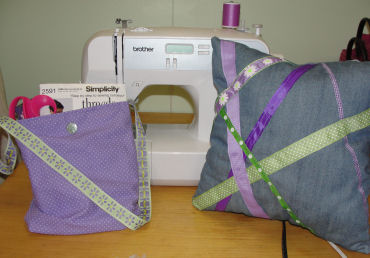 handmade purple ribbon pillow and lined shoulder bag sitting next to a sewing machine