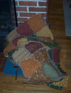 fall colored raggedy quilt against brick