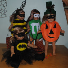 a group of american girl dolls in handmade halloween costumes