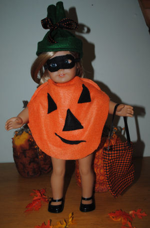 an american girl doll wearing a Halloween costume which is a handmade pumpkin costume with a black mask