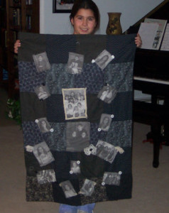 girl showing a black and white quilt she made with memory photos on it